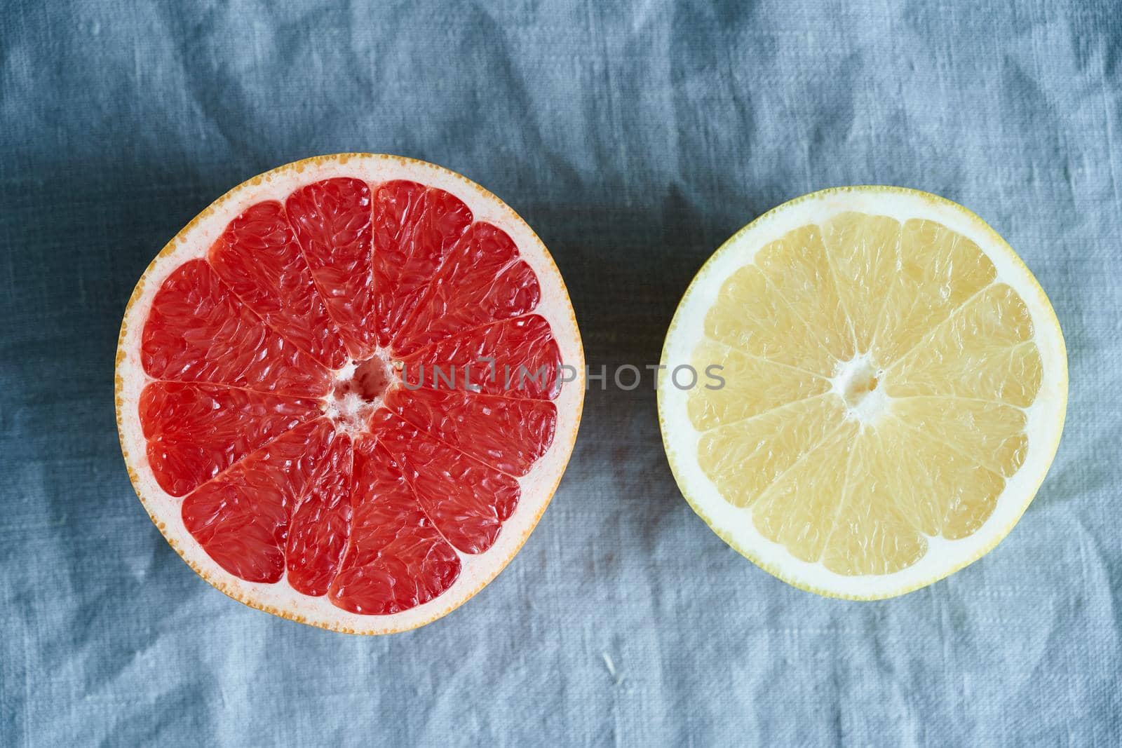 Two halves of red and white grapefruit, bright circles on a dark gray linen background. citrus fruits, banner
