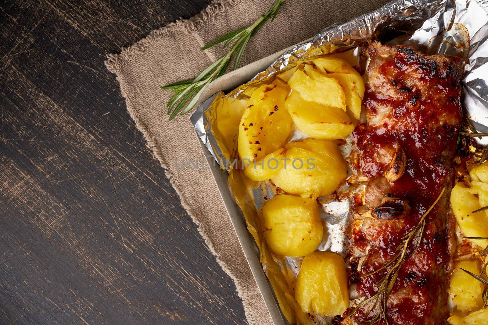 Spicy barbecue pork ribs and crushed smashed potatoes. Slow cooking recipe. Pickled Roasted Pork Meat on foil in tray, copy space