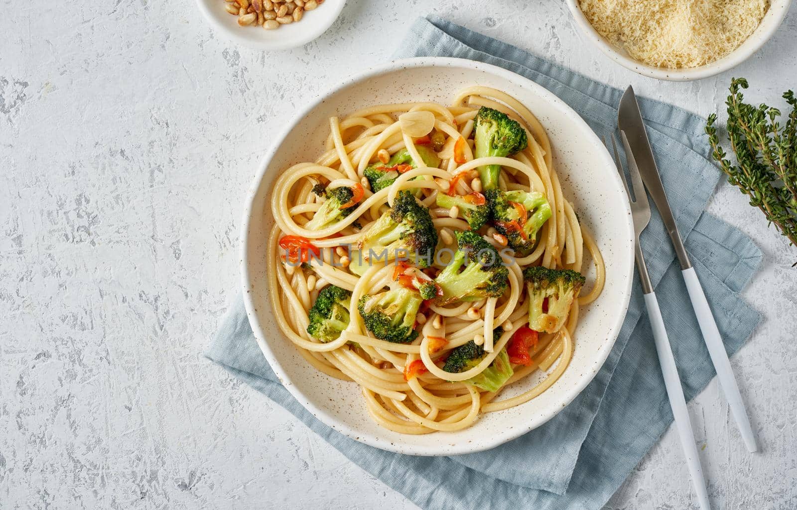 Spaghetti pasta with broccoli, bucatini with peppers, garlic, pine nuts. Food for vegans, vegetarians. Healthy dietary Mediterranean food. Light white table. Top view, copy space
