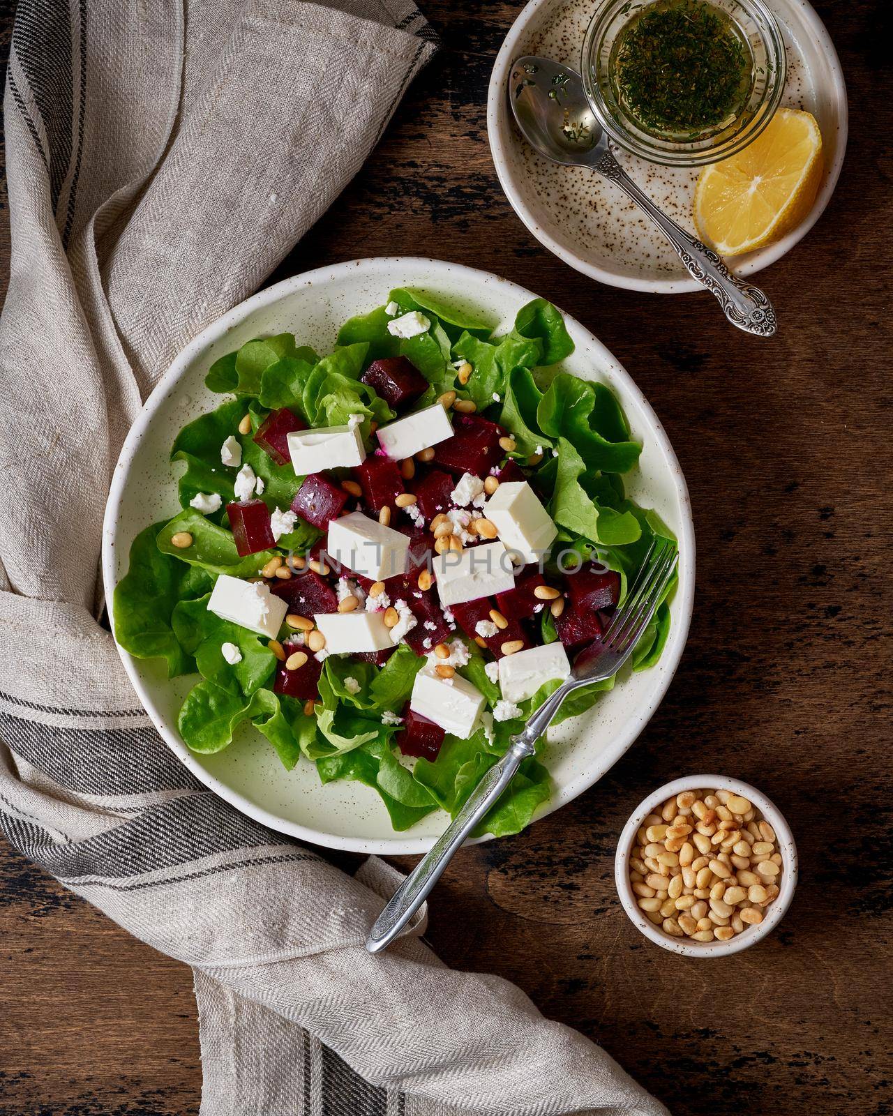 Healthy salad with beet, curd, feta and pine nuts, lettuce. Low carb keto ketogenic dash diet. Dark food photography. Vertical, top view