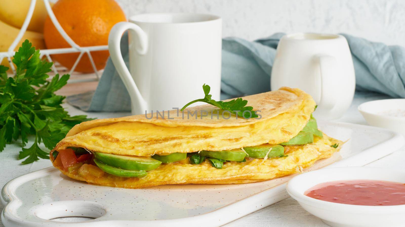 Trendy breakfast with whole quesadilla and eggs, trending food with omelet, cheese, peppers, tomatoes, avocado. Simple and easy lunch, side view