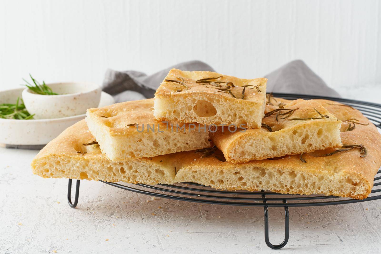Focaccia, pizza, italian flat bread with rosemary and olive oil on grid by NataBene