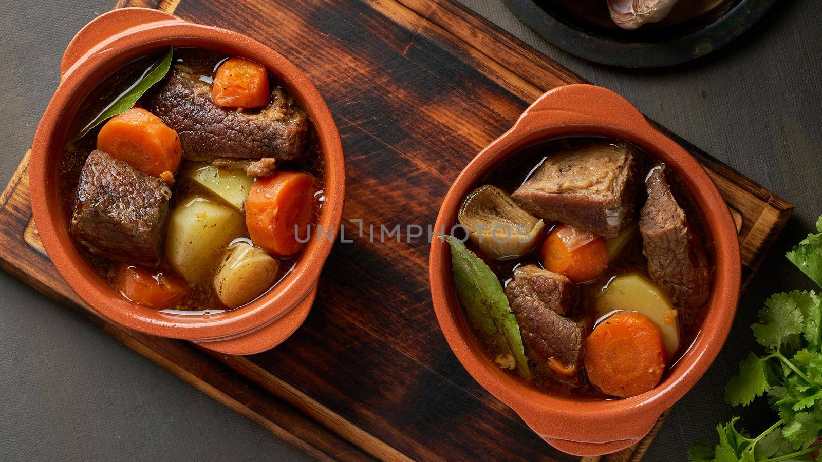 Goulash with large pieces of beef and vegetables. Burgundy meat. Slow stewing, cooking in pot or cast-iron pan. Dark backdrop