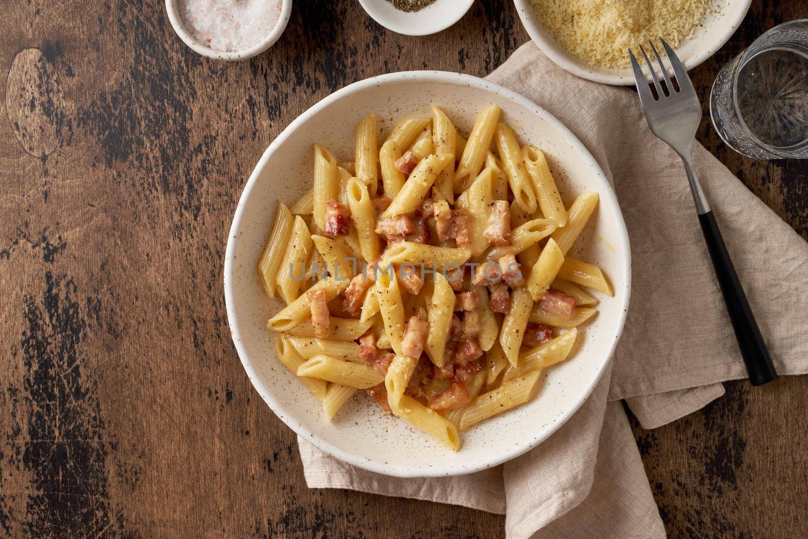 Carbonara pasta. Penne with pancetta, egg, parmesan cheese and cream sauce. Traditional italian cuisine. Top view, copy space