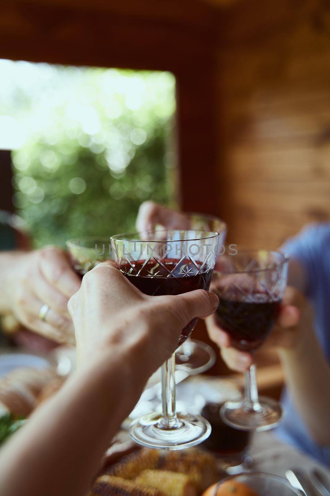 Cropped hands of unrecognizable people holding glasses full of beverage celebration event concept of holiday weekend leisure on wooden background