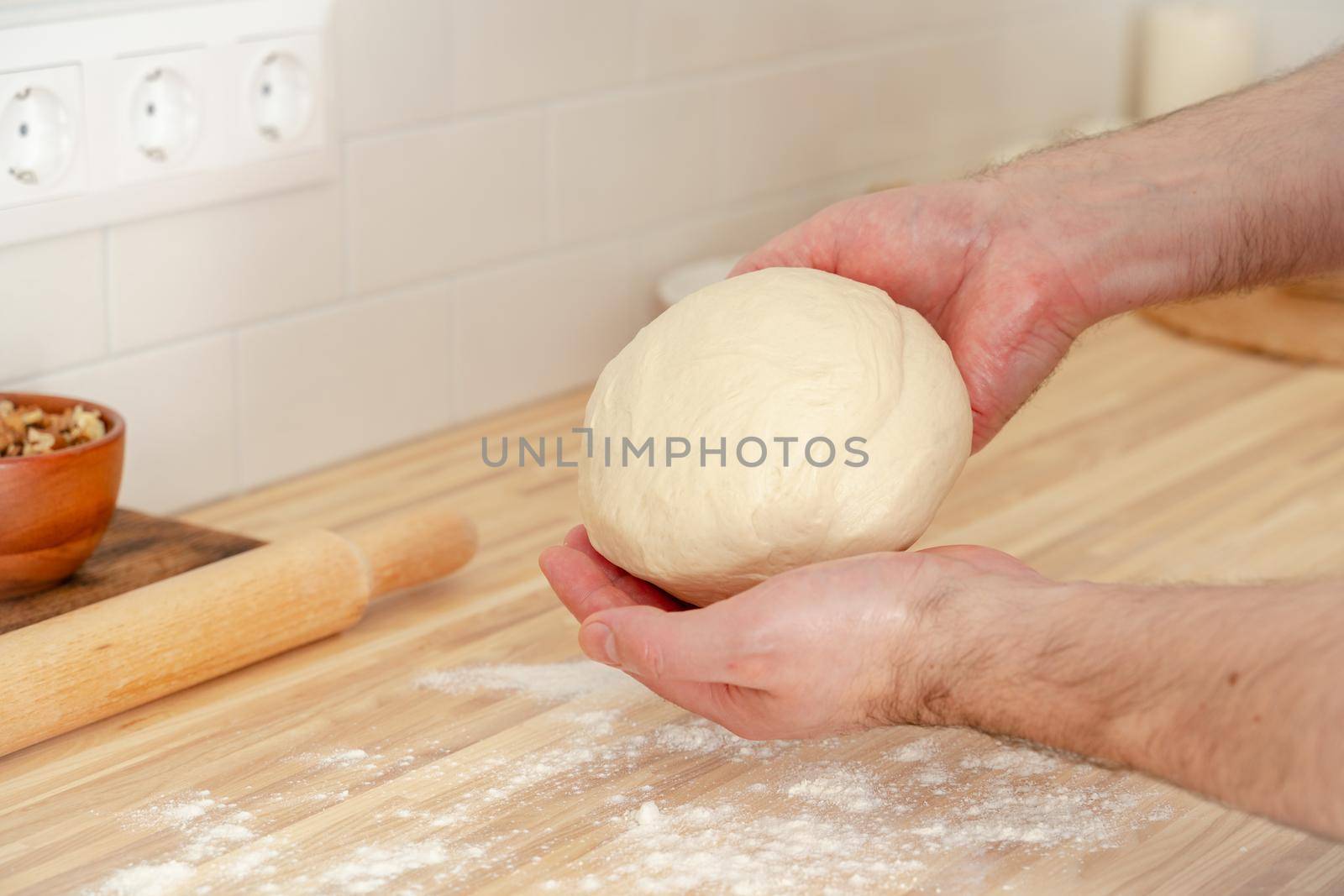 Faceless man kneading dough on kitchen table at home, apartment, flour, scales by NataBene