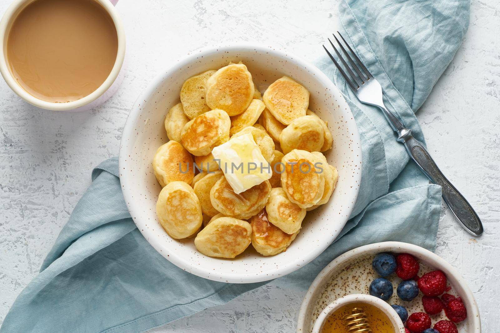 Pancakes cereal, trendy food, tiny thin funny crumpet, children's food. Breakfast with drink, white table, bright morning, top view