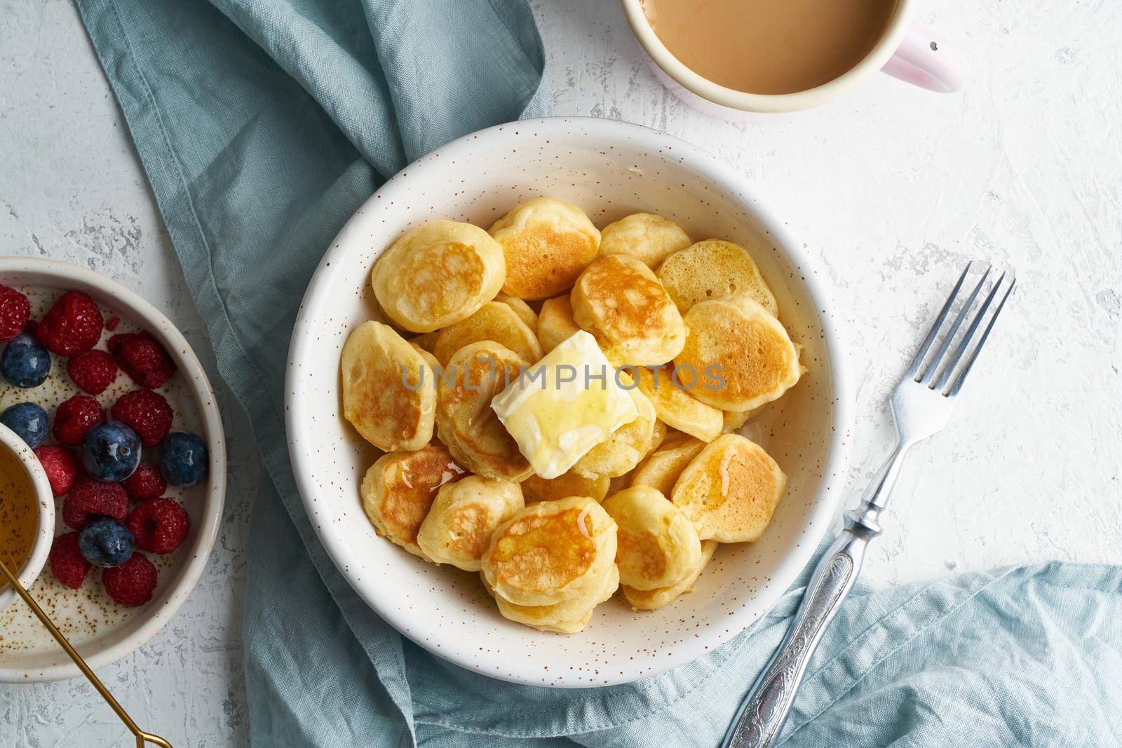 Pancakes cereal, trendy food, tiny thin funny crumpet, children's food. Breakfast with drink, white table, bright morning, top view