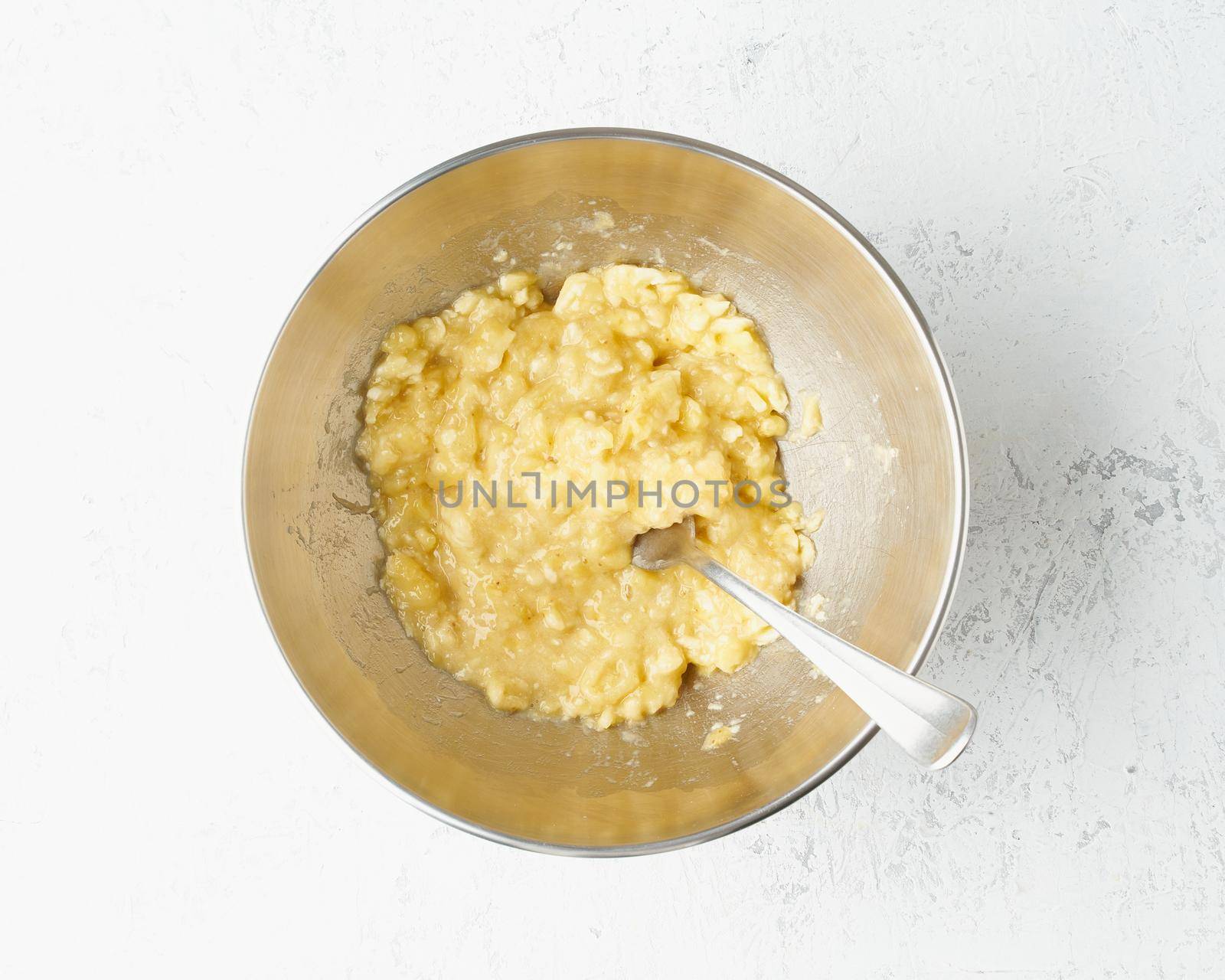 Homemade Banana bread. Dough for cake. Step by step recipe. Step 2. Mashed banana. Top view, white table.