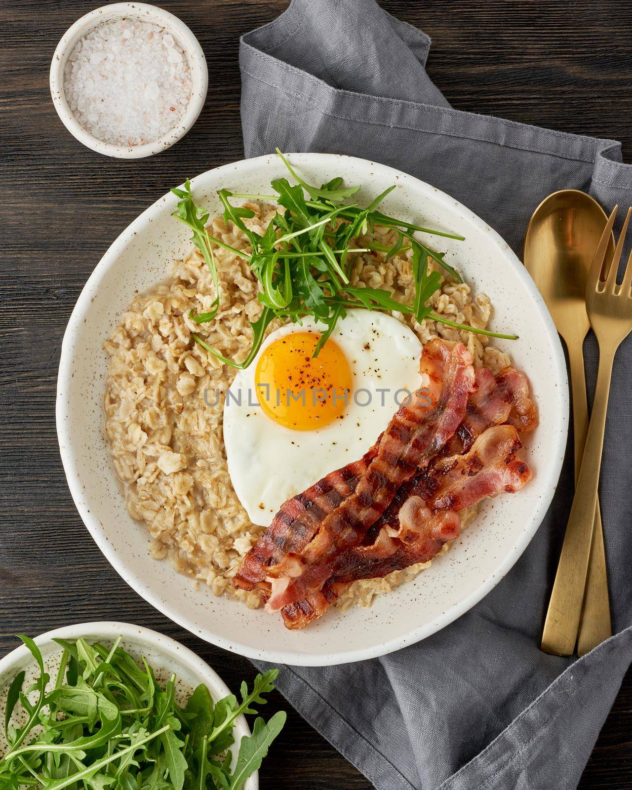Oatmeal, fried egg and fried bacon. Brutal man sport breakfast. Hearty fat high-calorie breakfast, source of energy. Balance of proteins, fats, carbohydrates. Balanced food. Vertical