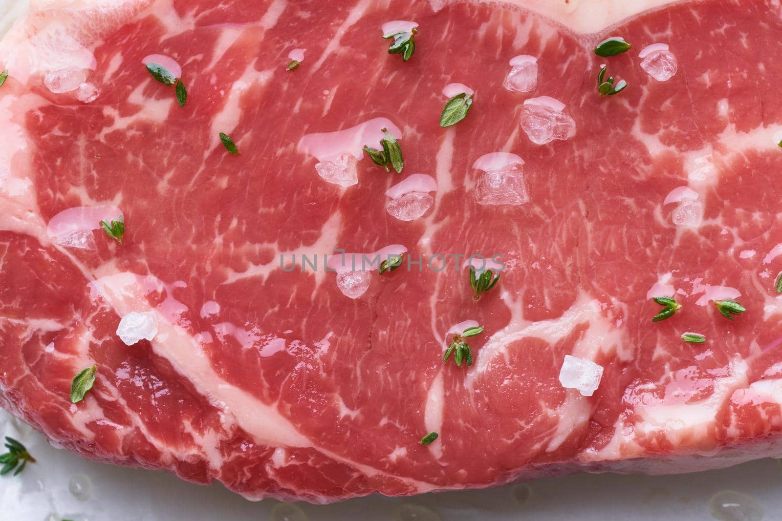 Big whole piece of raw beef meat, striploin. Steak with seasoning, oil and salt. Top view, close up, macro