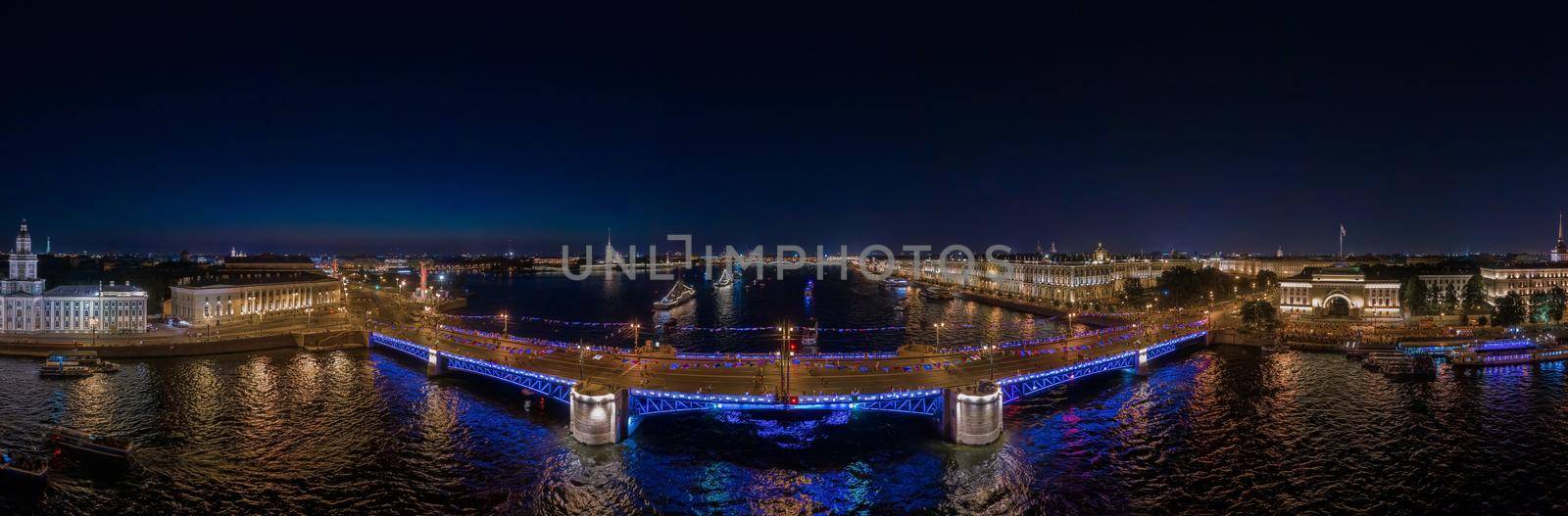 night landscape of festivities on the day of the Russian Navy, picturesque night illumination of buildings, warships and drawbridges, many people walk in the absence of automobile traffic. High quality photo