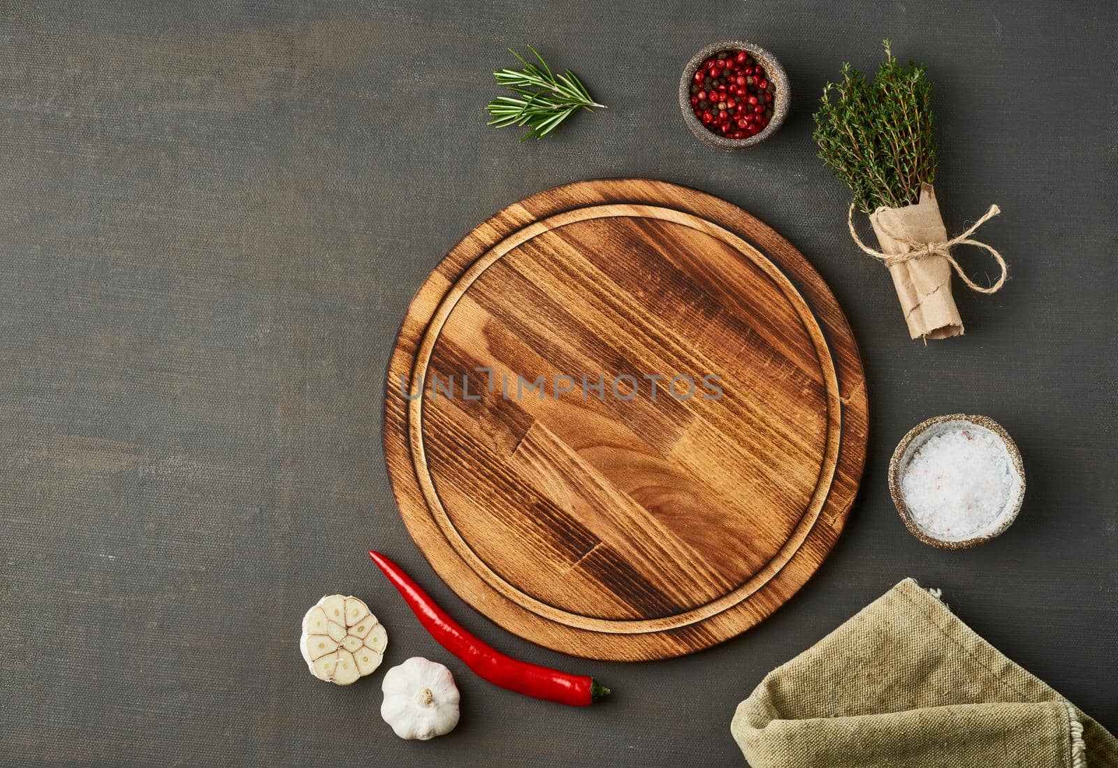 Food seasoning background. Menu, recipe, mock up, banner. Round wooden cutting board, spices, herbs on dark brown backdrop. Top view, copy space.