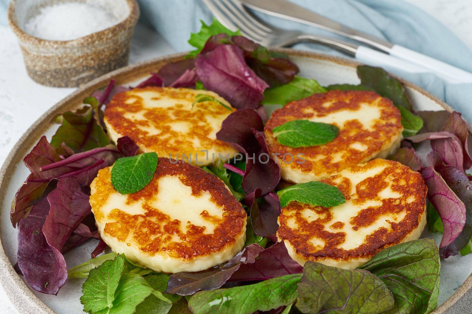 Cyprus roasted halloumi with salad mix, beet tops. Lchf, pegan, fodmap, paleo, scd, keto, ketogenic diet. Balanced food, clean eating recipe. White background, side view