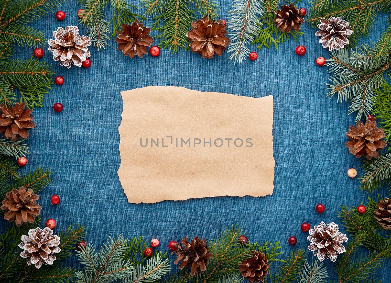 Christmas and Happy New Year dark blue background with craft paper for text. Frame for recipe, menu with fir branches, cones, cranberry berries. Textile backdrop with copy space.