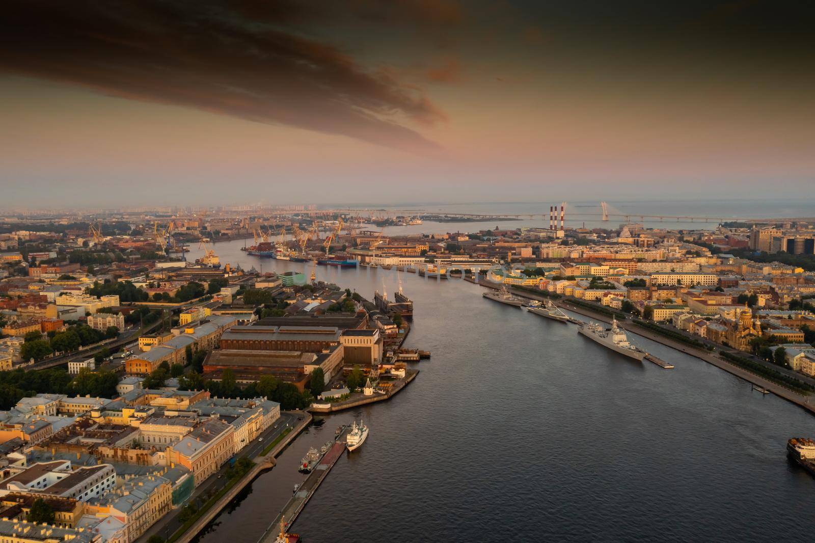 Aerial morning cityscape with warships in the waters of the Neva River before the holiday of the Russian Navy at sunrise, shipyard cranes in the background, cable-stayed bridge, embankment. High quality 4k footage