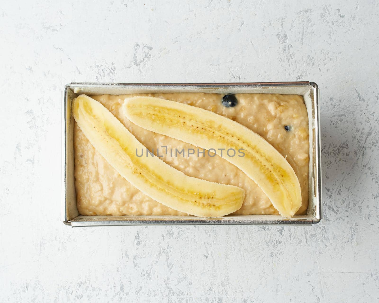 Homemade Banana bread. Dough for cake in pan loaf. Step by step recipe. Step 11. Top view, white table.