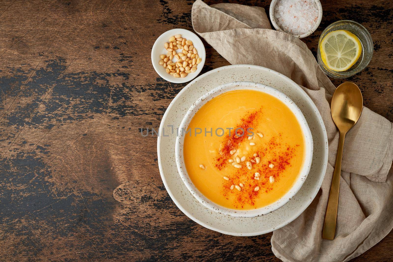 Autumn pumpkin soup with smoked paprika, pine nuts, vegetarian dish, healthy and dieting food on dark background, top view, copy space