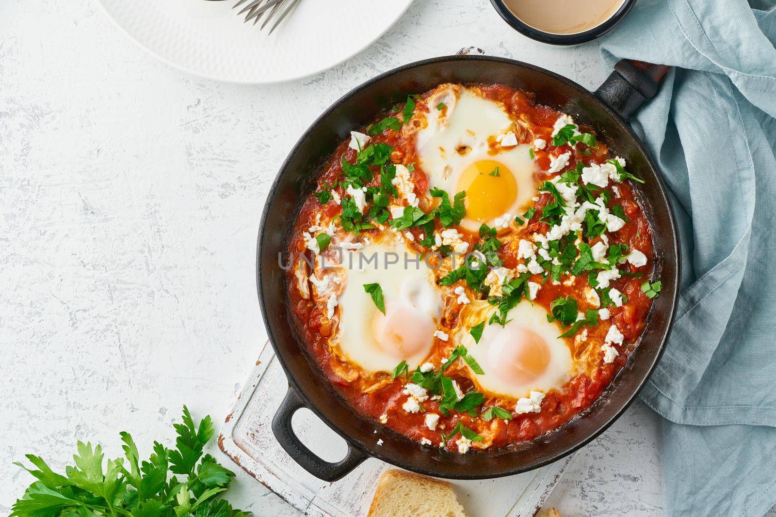 Shakshouka, eggs poached in sauce of tomatoes, olive oil, peppers, onion and garlic, Mediterranean cousine. Keto meal, FODMAP recipe, low carb. Top view, copy space