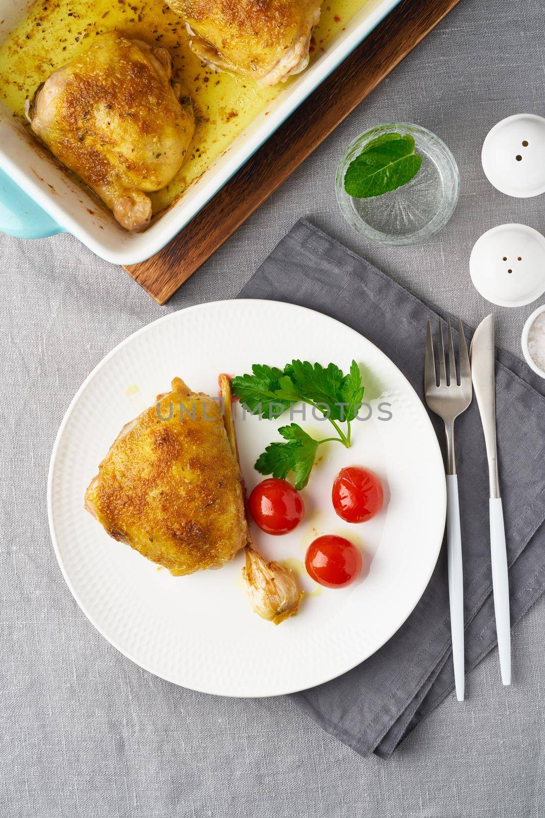 Chicken thighs baked with turmeric, tomatoes and garlic. Fried chicken is on plate by NataBene