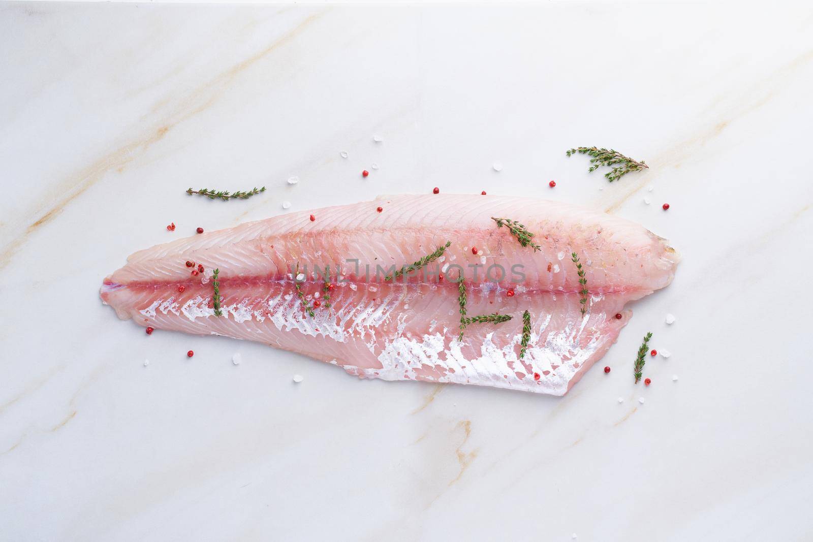 Fresh raw pike perch fish fillet on marble dark brown table. Top view, close up