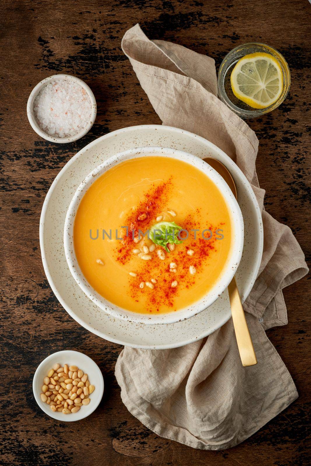Autumn pumpkin soup with smoked paprika, pine nuts, vegetarian dish, healthy and dieting food on dark background, top view, vertical