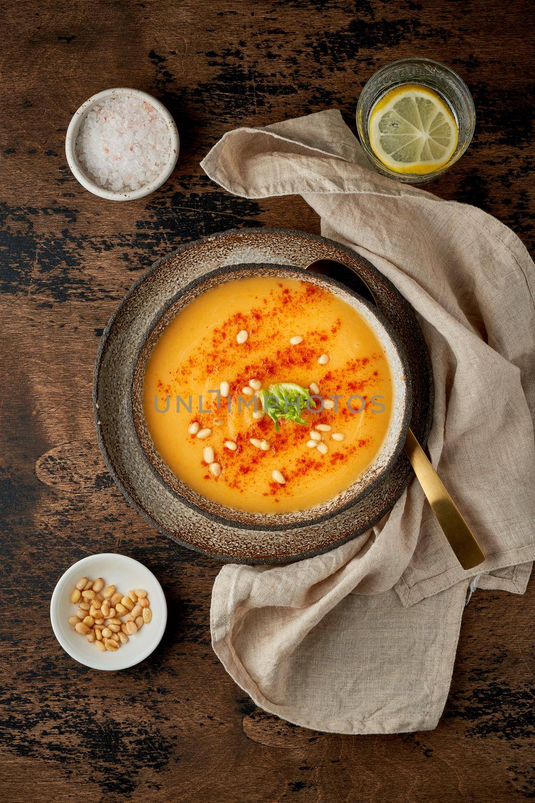 Autumn pumpkin soup with smoked paprika, pine nuts, vegetarian dish, healthy and dieting food on dark background, top view, vertical