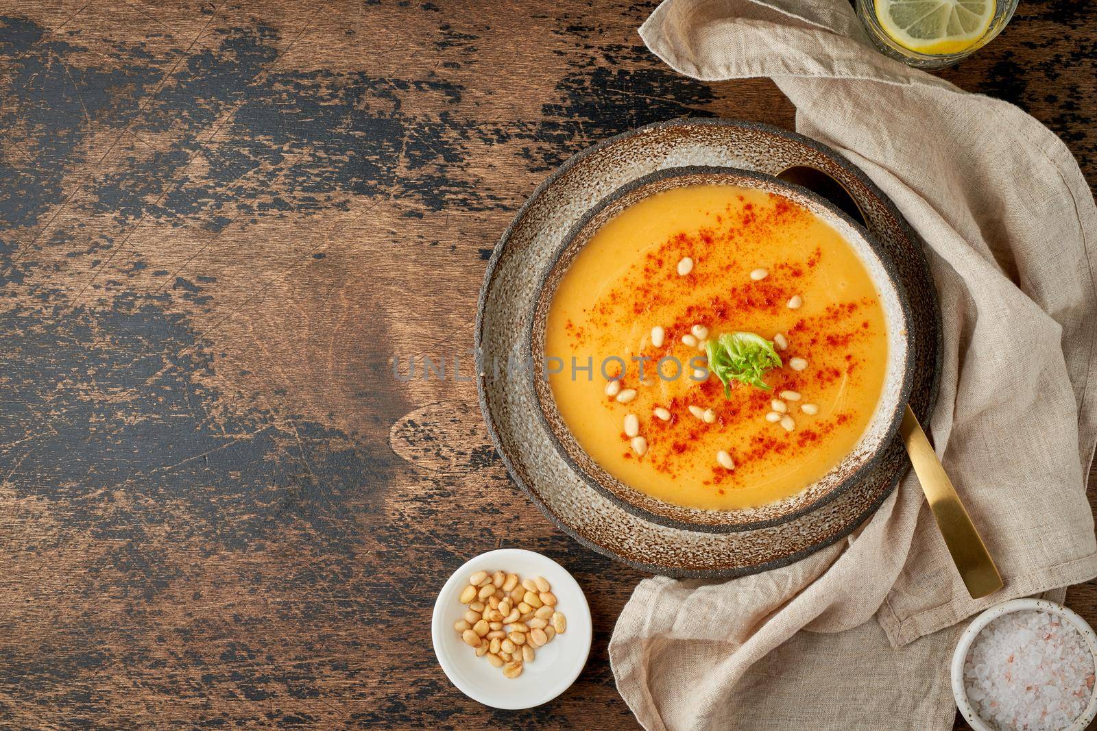 Autumn pumpkin soup with smoked paprika, pine nuts, vegetarian dish, healthy and dieting food on dark background, top view, copy space