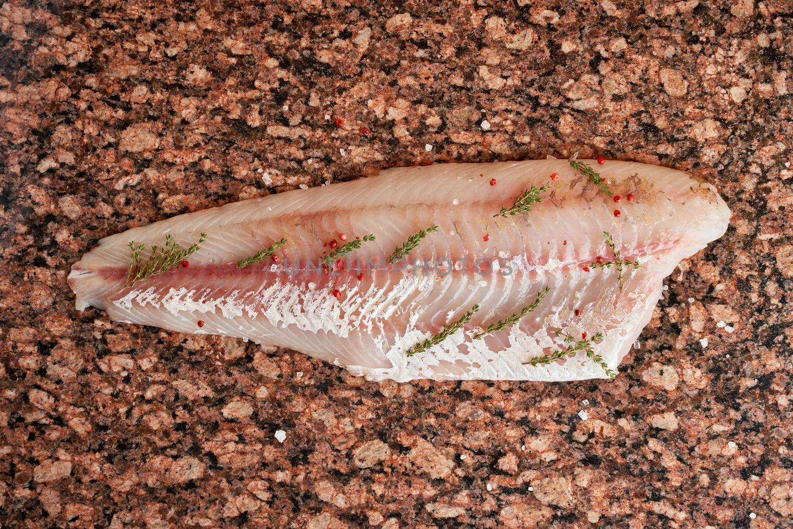 Fresh raw pike perch fish fillet with thyme on marble dark brown table. Top view