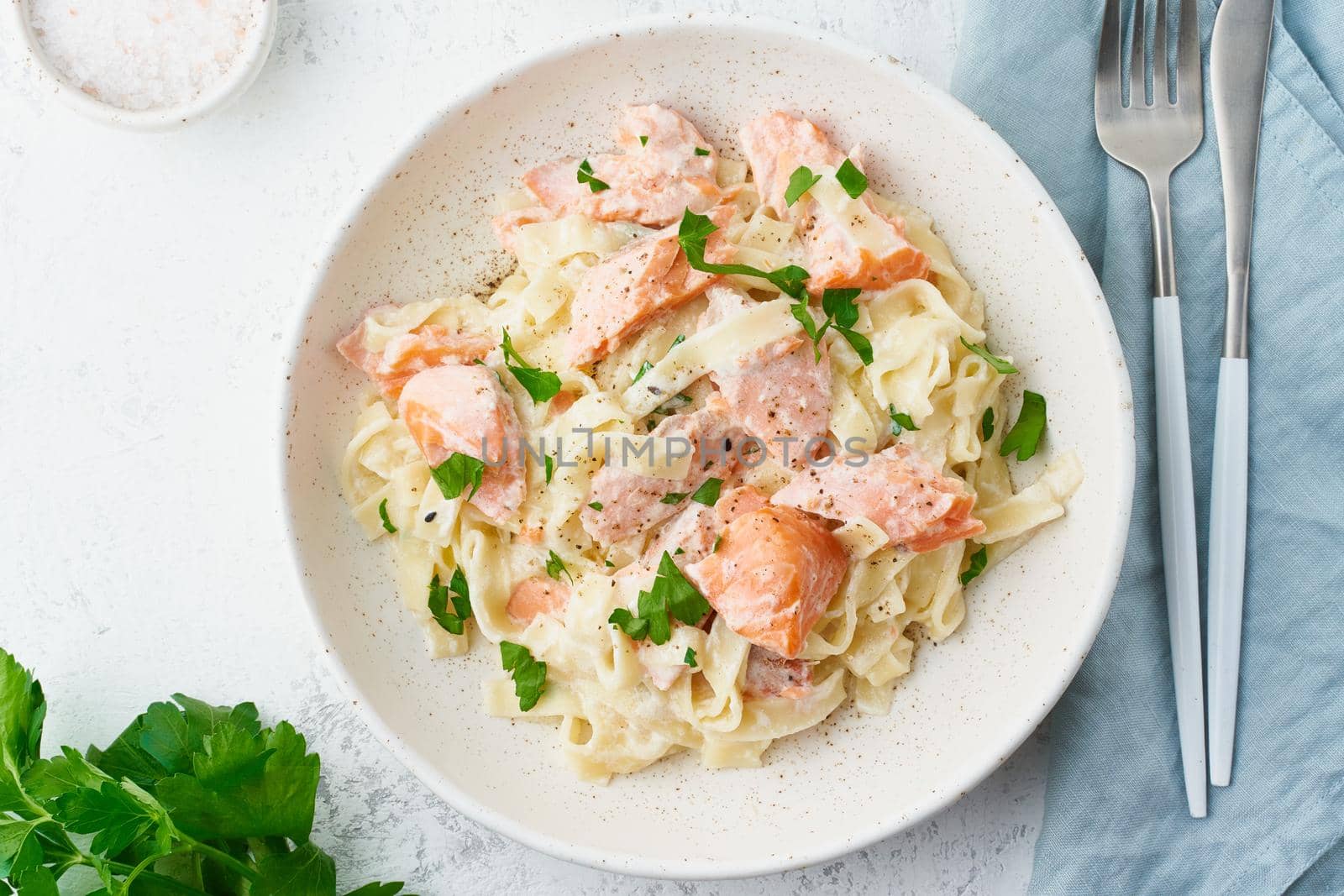 Salmon pasta, tagliatelle with fish and creamy sauce. Italian dinner with seafood. White background, top view