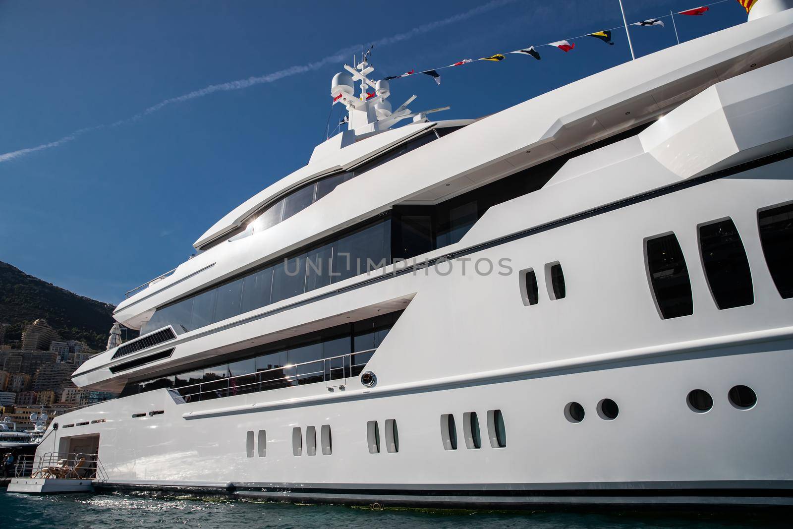 The top deck of a huge yacht at sunny day, glossy board of the boat, The chrome plated handrail, megayacht is moored in port, sun reflection on glossy board. High quality photo