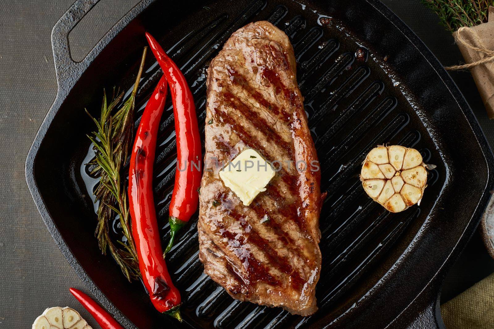 Keto ketogenic diet beef well done steak, fried striploin on grill pan. Paleo food recipe with grilled meat, butter and seasoning. Close up, top view, macro, banner