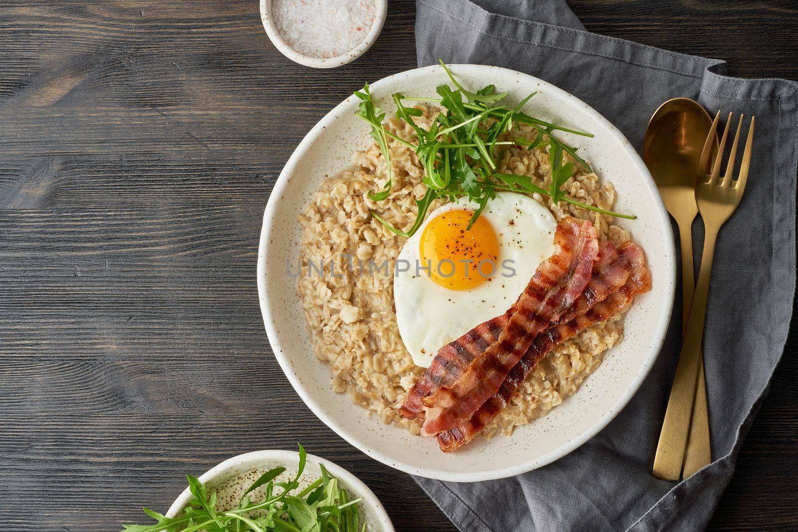 Oatmeal, fried egg and fried bacon. Brutal man sport breakfast. Hearty fat high-calorie breakfast, source of energy. Balance of proteins, fats, carbohydrates. Balanced food. Copy space