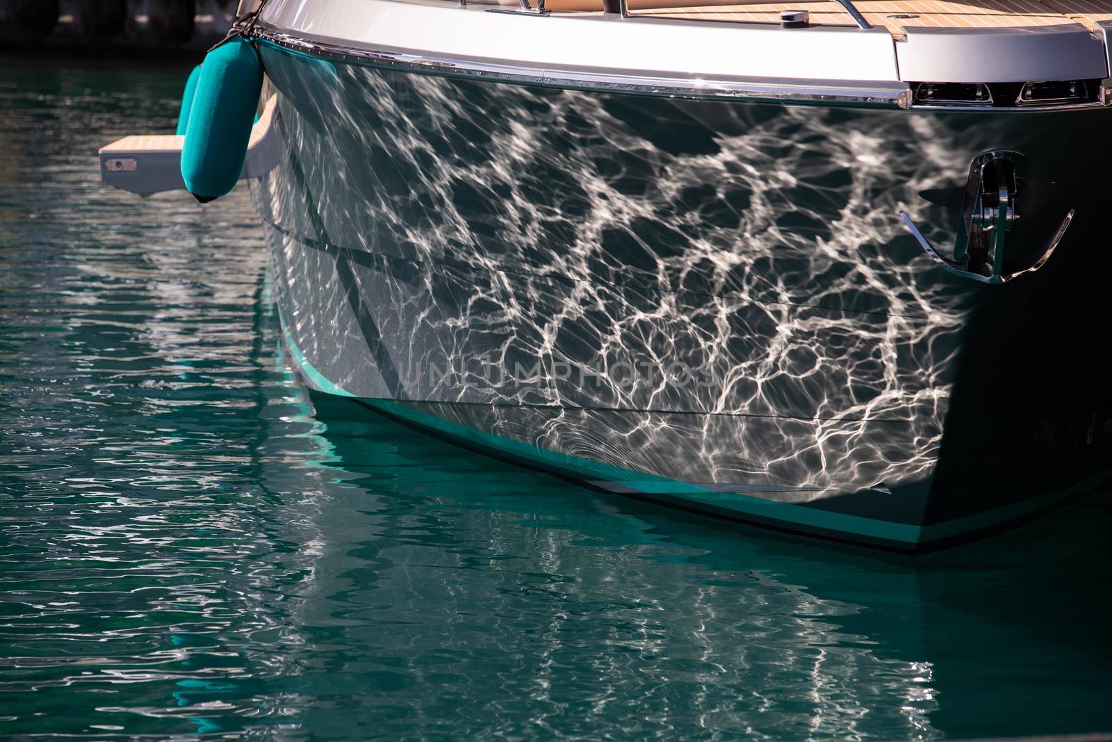 The mesmerizing reflection of the water on the glossy side of a huge yacht anchored, chrome details. High quality photo