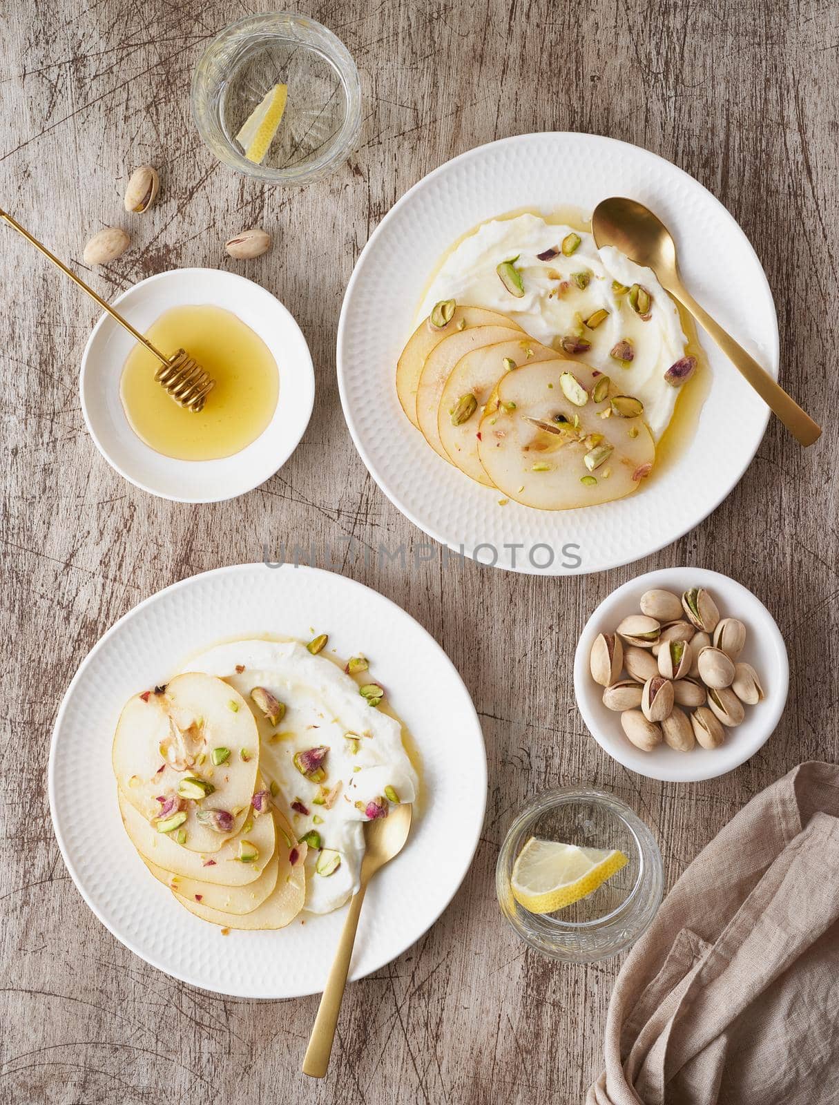 Ricotta with pears, pistachios and honey or maple syrup on two white plate by NataBene