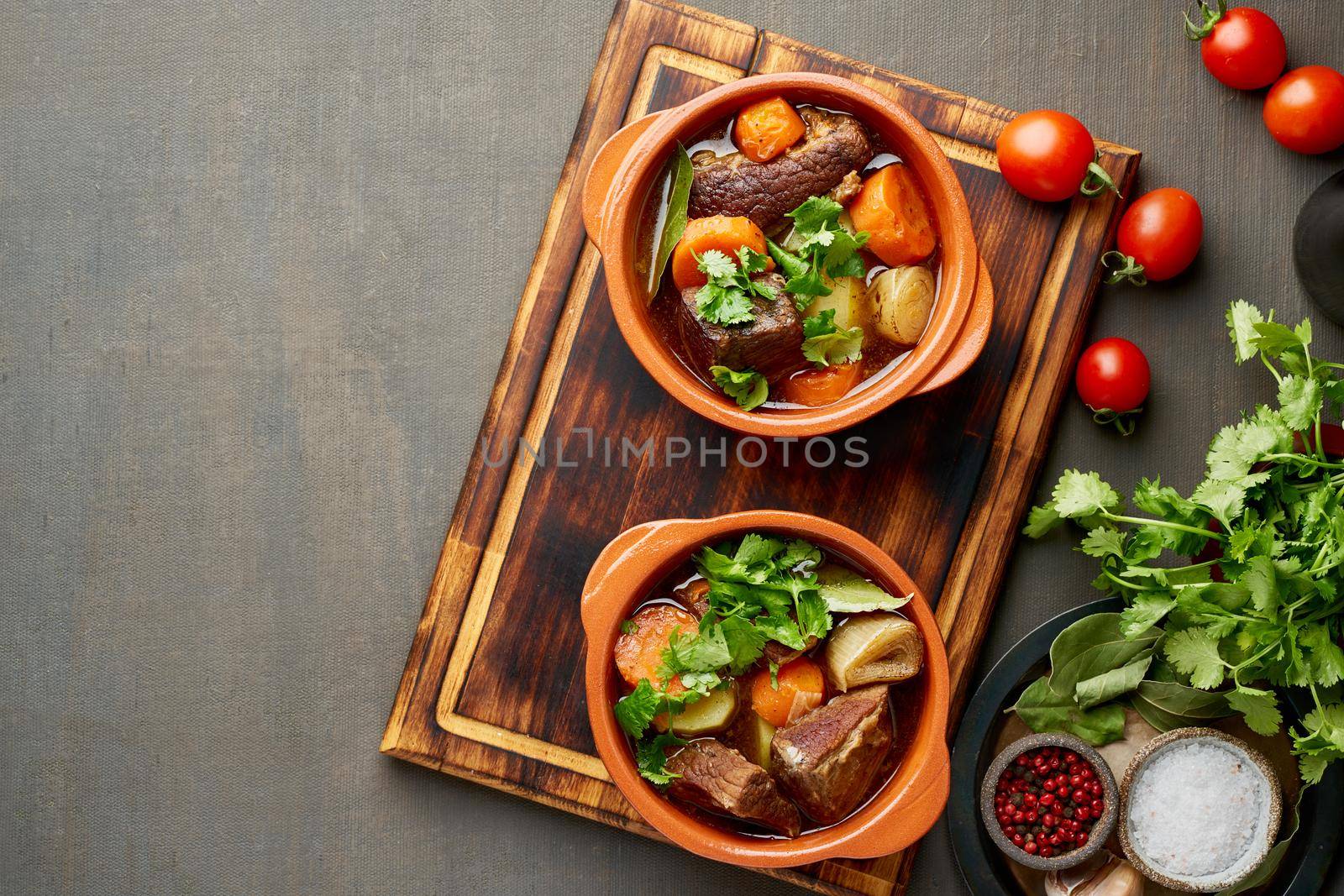 Goulash with large pieces of beef and vegetables. Burgundy meat. Slow stewing, cooking in pot or cast-iron pan. Dark brown backdrop. top view, copy space