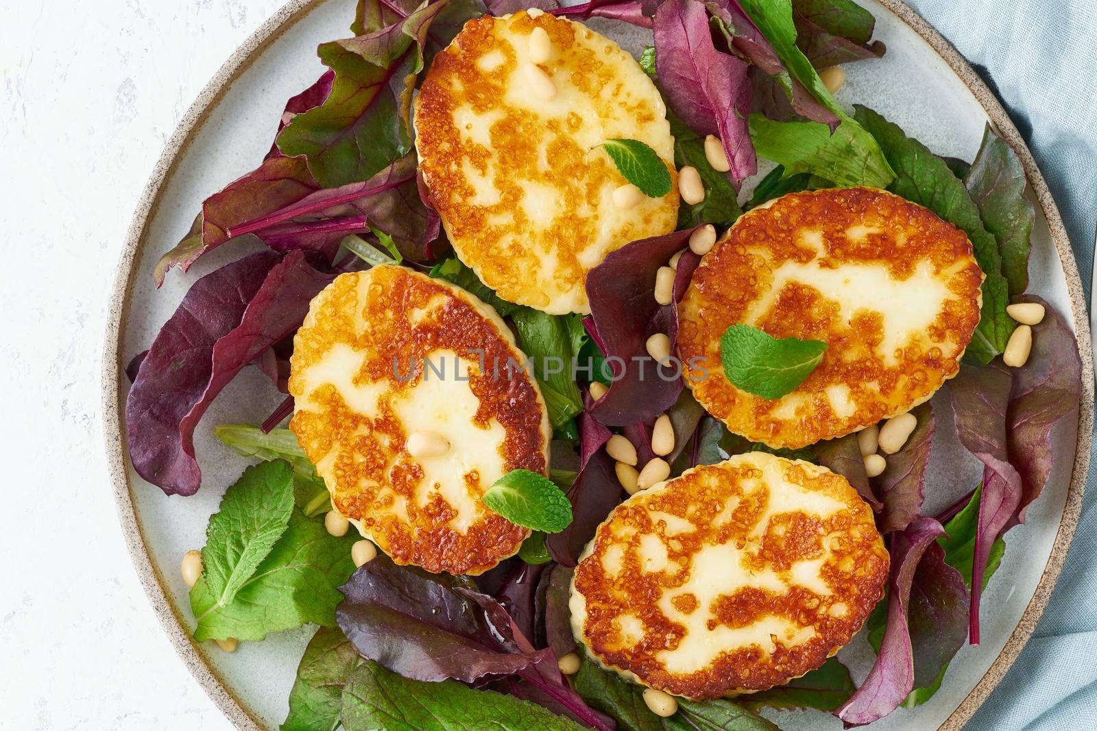 Cyprus fried halloumi with salad mix, beet tops. Lchf, pegan, fodmap, paleo, scd, keto, ketogenic diet. Balanced food, clean eating recipe. Top view, a white background, close up