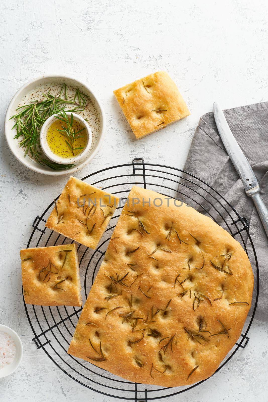 Focaccia, pizza, italian flat bread with rosemary and olive oil on grid by NataBene