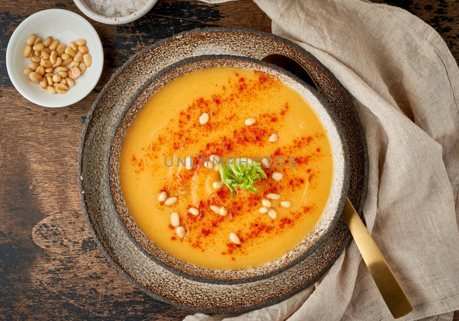 Autumn pumpkin soup with smoked paprika, pine nuts, vegetarian dish, healthy and dieting food on dark background, top view