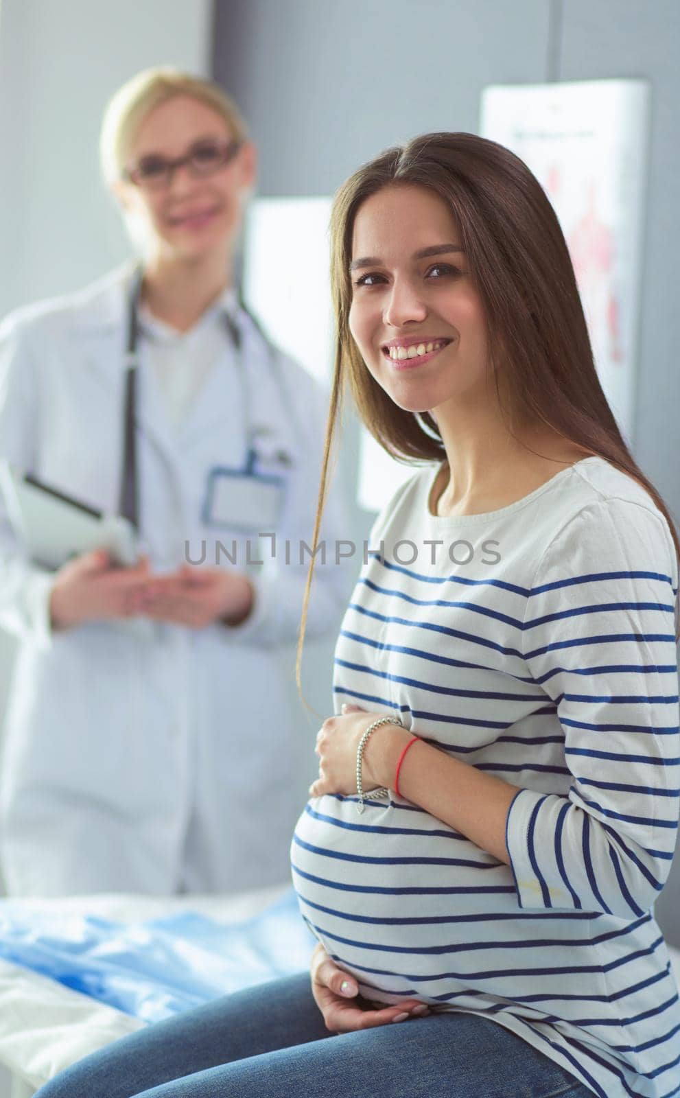 Beautiful smiling pregnant woman with the doctor at hospital.