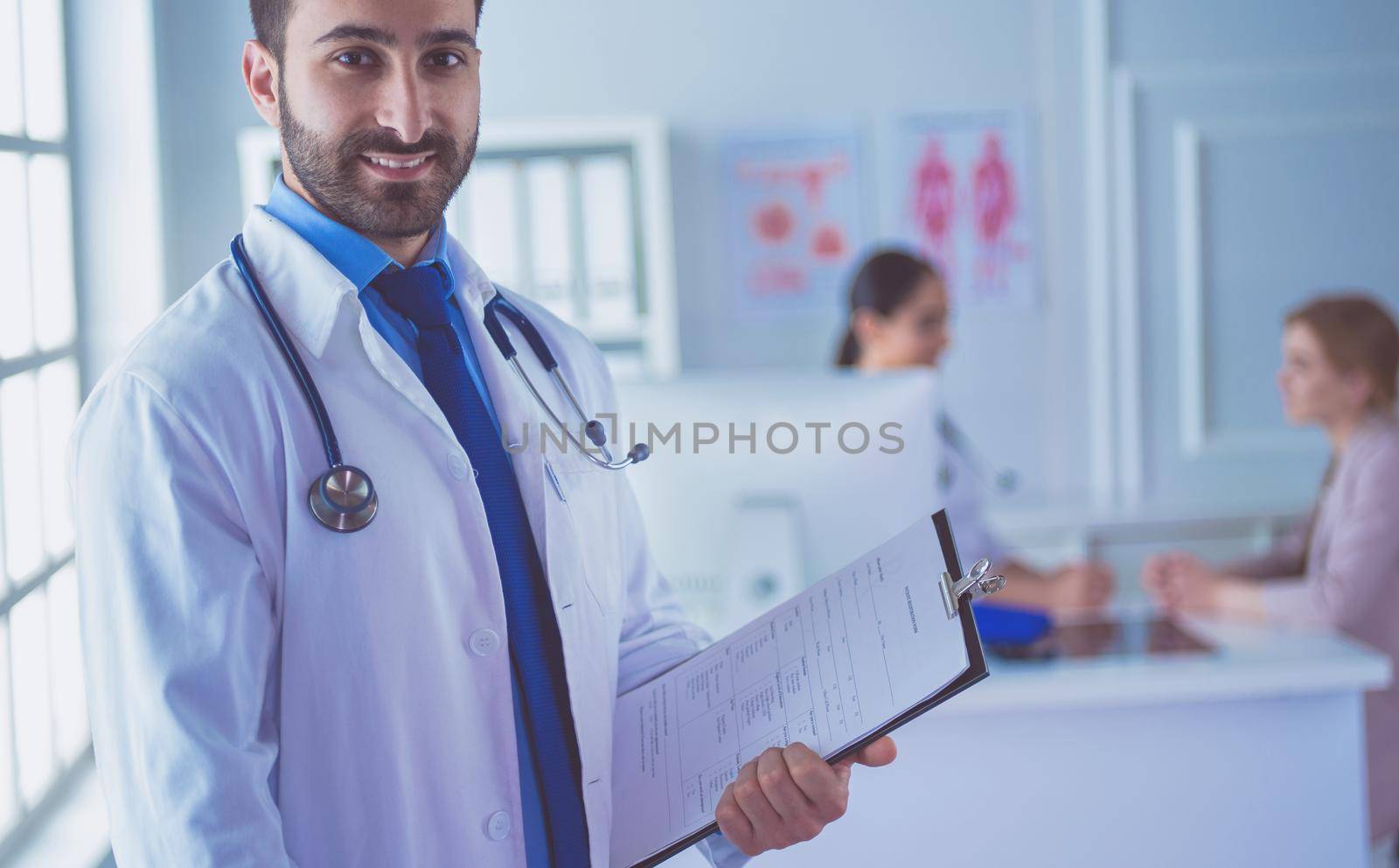 Smiling doctor man standing in front of his team and patient.