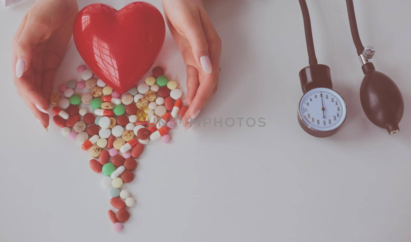 Cardiologist with red heart and stethoscope at table.
