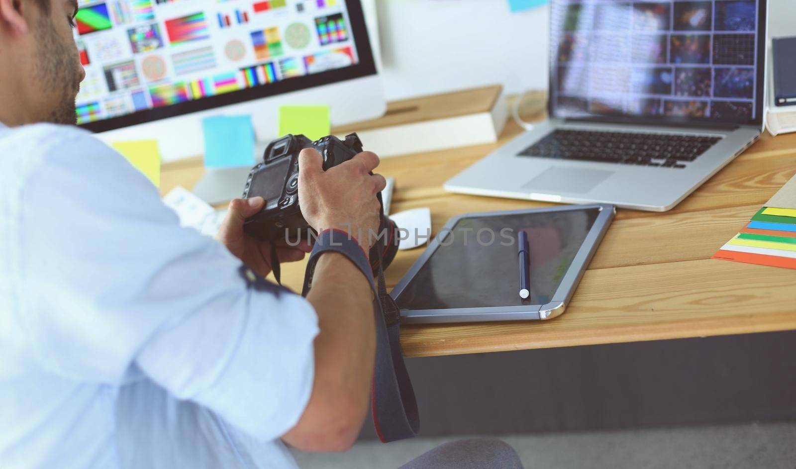 Portrait of young designer sitting at graphic studio in front of laptop and computer while working online.