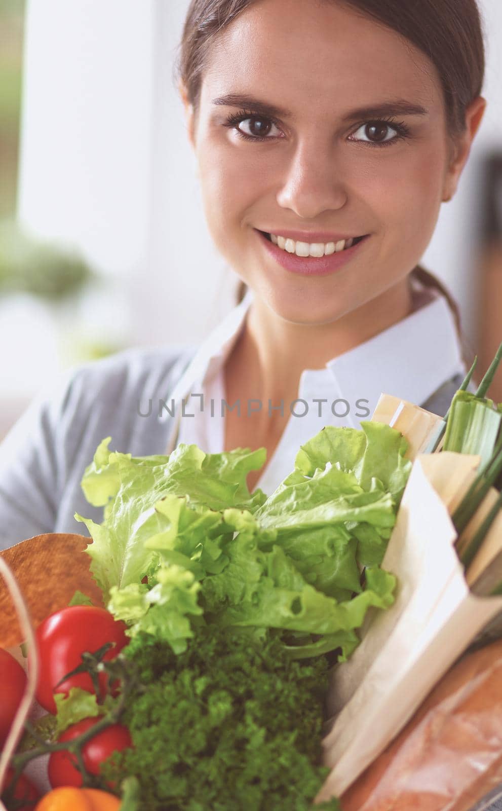 Young woman holding grocery shopping bag with vegetables.