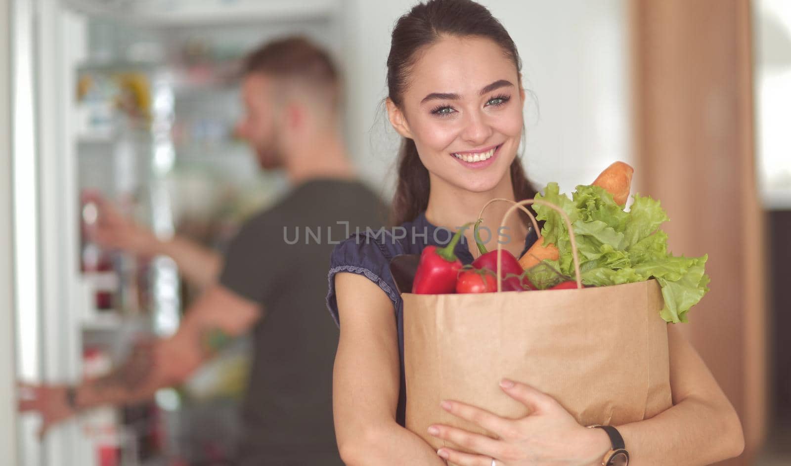 Young couple in the kitchen , woman with a bag of groceries shopping.