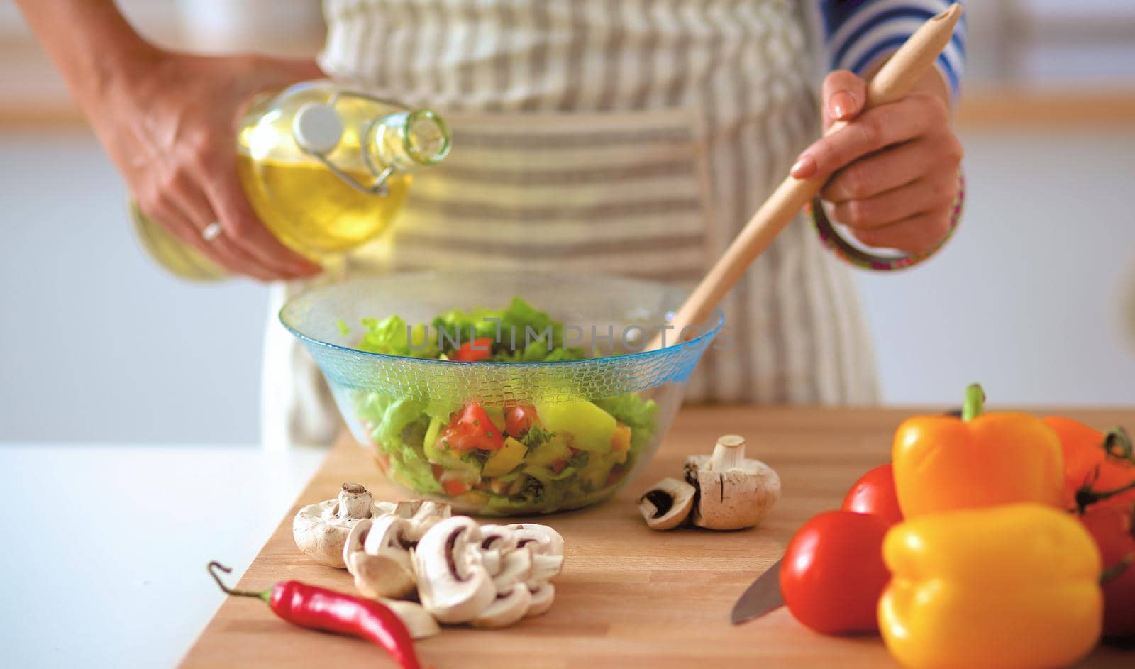 Young woman mixing fresh salad .