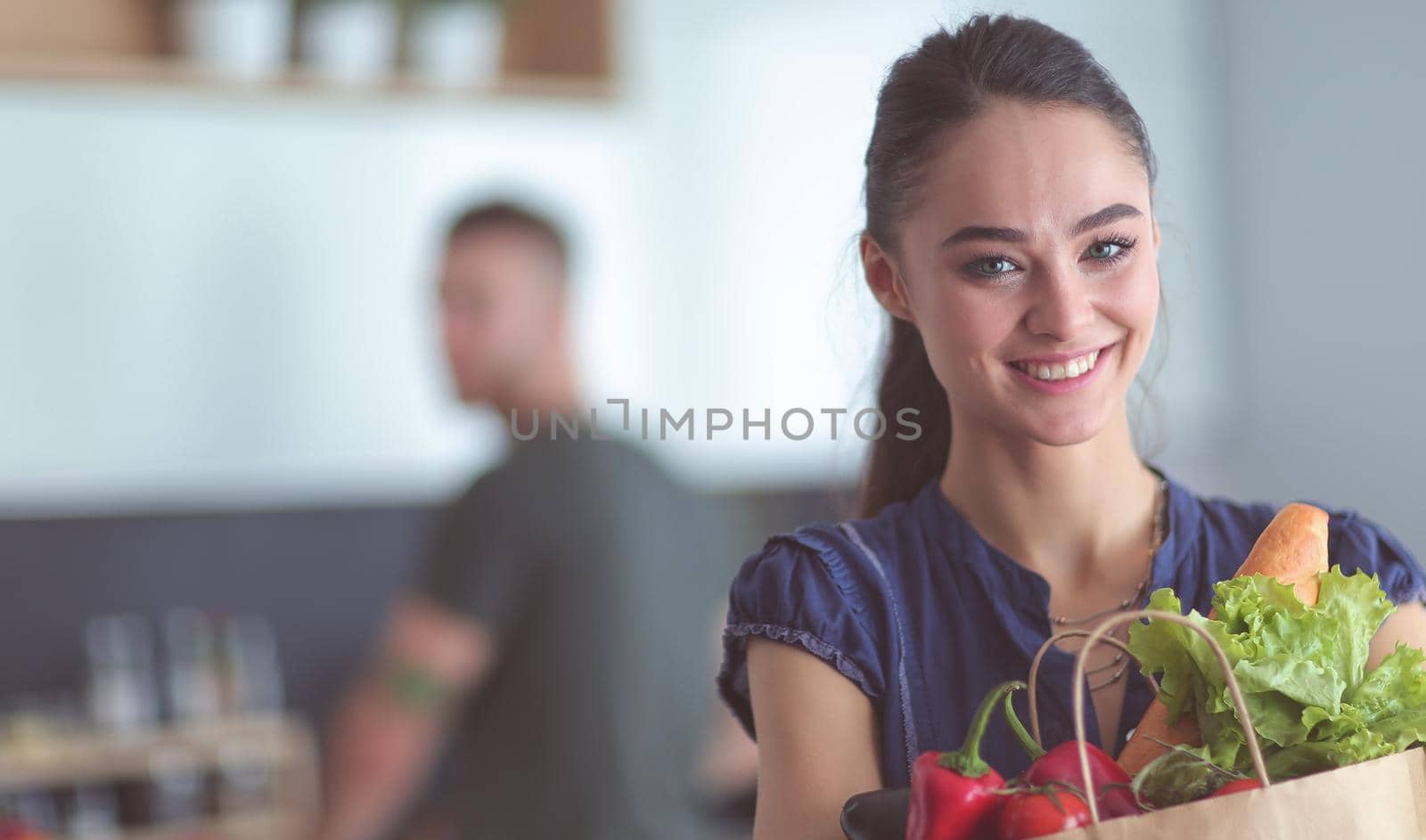 Young couple in the kitchen , woman with a bag of groceries shopping.