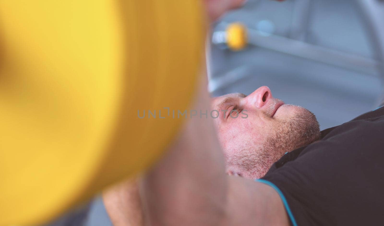 Young man lifting the barbell in the gym with instructor .