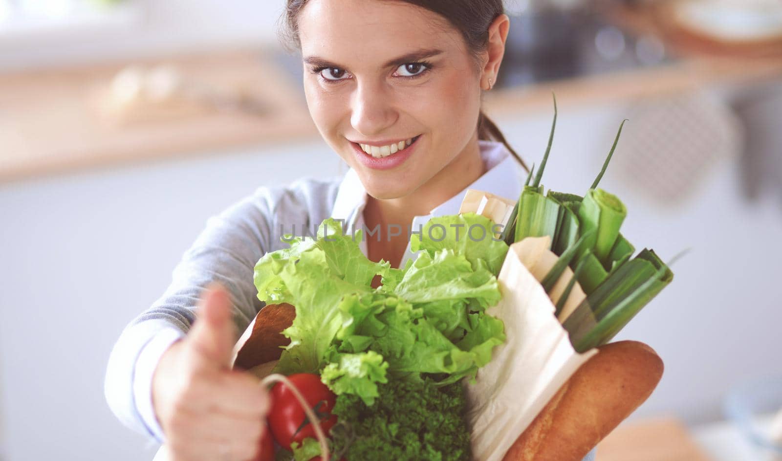 Young woman holding grocery shopping bag with vegetables .Standing in the kitchen.
