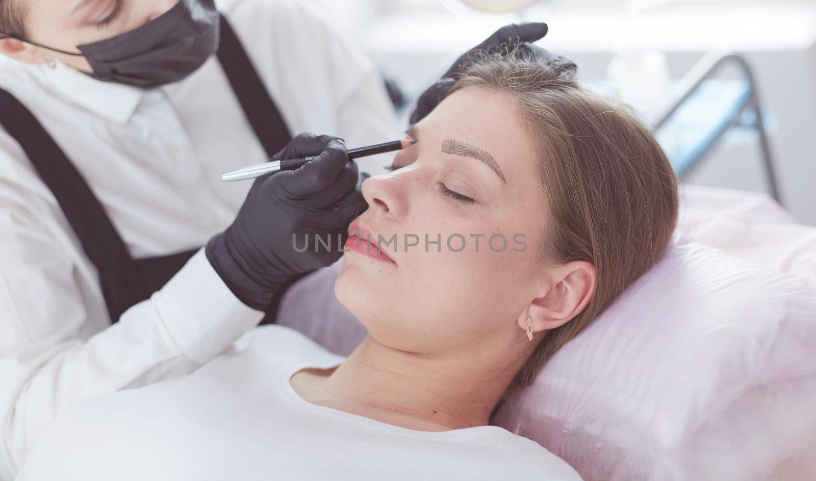 Cosmetologist applying permanent make up on eyebrows.